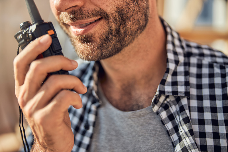 man-communicating-on-the-wireless Professional using a wireless radio to maintain effective workplace communication.