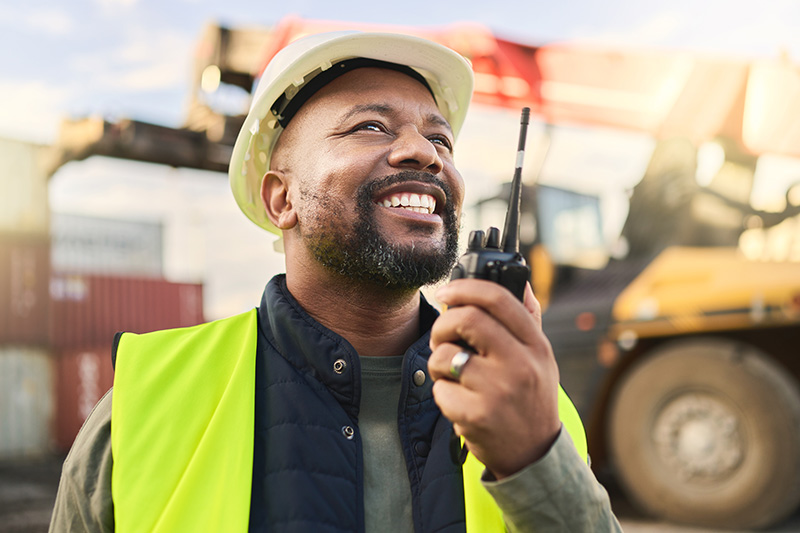 man-using-radio-communication-transportation Transportation worker using a radio to coordinate logistics and operations.